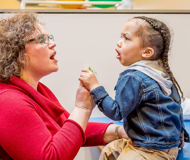 Female pediatric speech therapist worths with young child on speech techniques