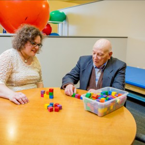 Female occupational therapist helps older man sort colored blocks on a table