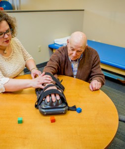 Older male patient works on hand therapy with female therapist