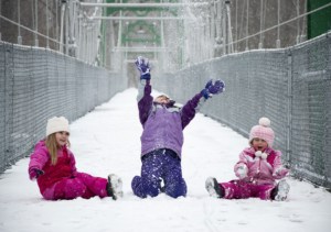 Three young girls in snowsuits play in the snow