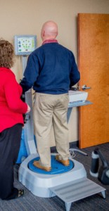 Female physical therapists works with older male patient on the Biodex balance system