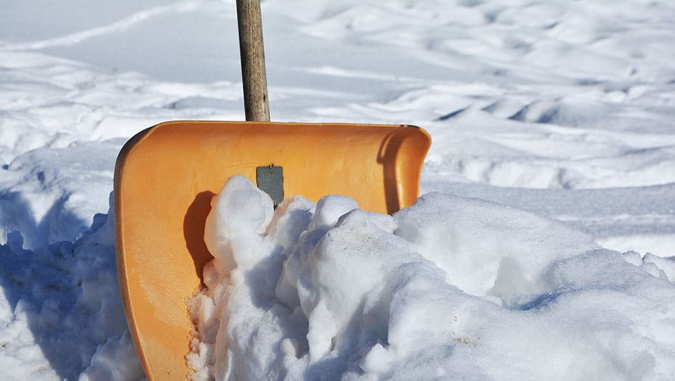 Orange shovel stuck in the snow