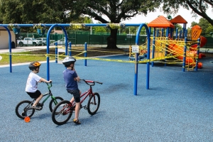 Two young boys ride bikes to the playground.