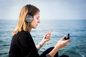 Woman relaxes listening to headphones with ocean in the background