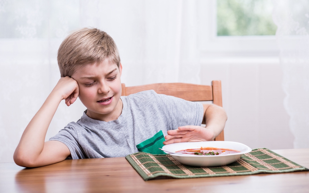 Young boy pushes away bowl of soup at lunchtime.